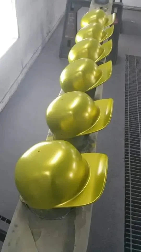Row of shiny gold hard hats lined up on a wooden surface in an industrial setting