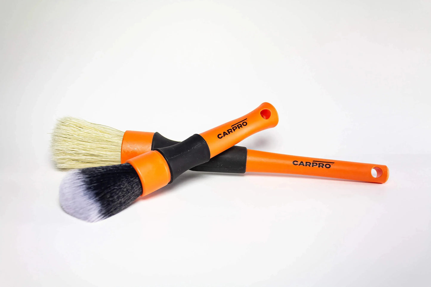 Two CarPro detailing brushes with orange handles on white background, used for car cleaning