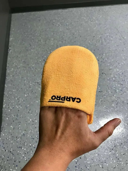 Hand wearing an orange microfiber applicator mitt with CARPRO logo on speckled gray floor