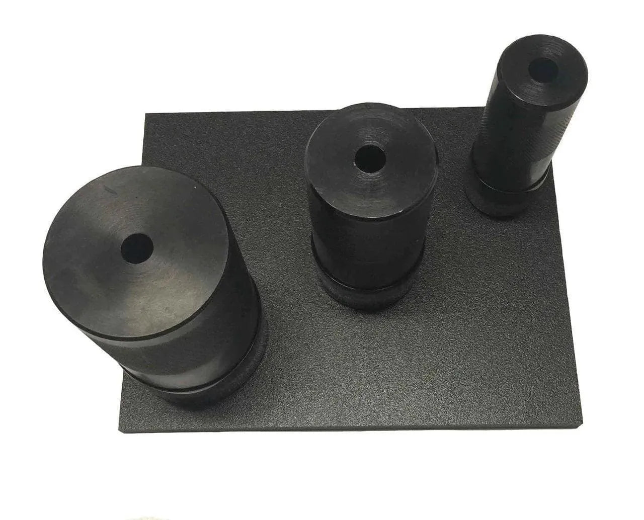 black rubber punch board with three cylindrical punch tools of different sizes on textured base