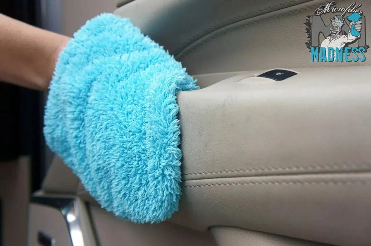 Blue microfiber cleaning mitt wiping beige car door interior panel with logo in corner
