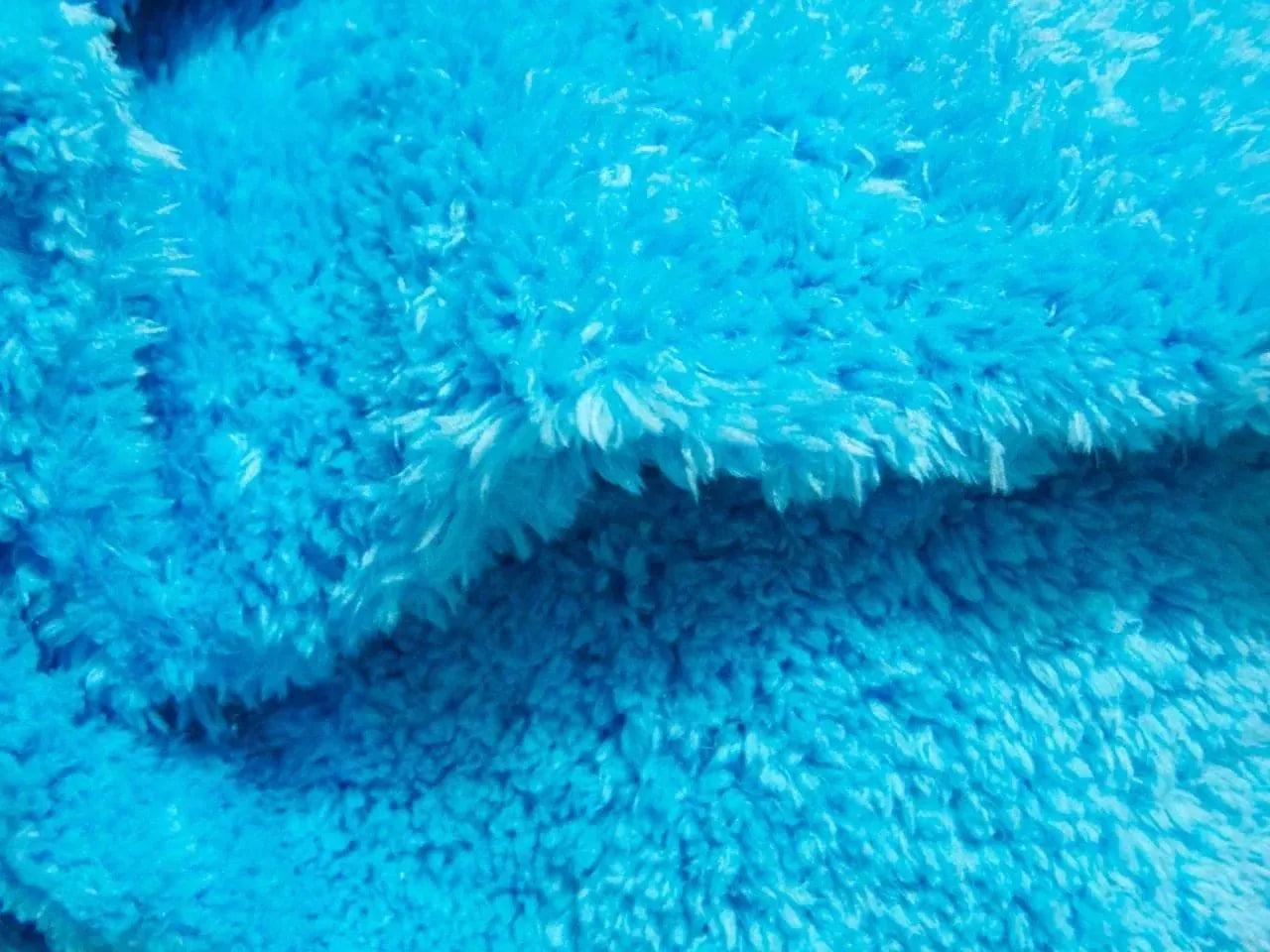 Close-up of bright blue microfiber cloth with thick, fluffy texture and dense fibers