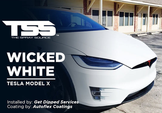 White Tesla Model X parked outside a building with tinted windows and black accents