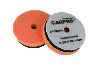 Pair of orange CarPro polishing pads with center holes and gray backing