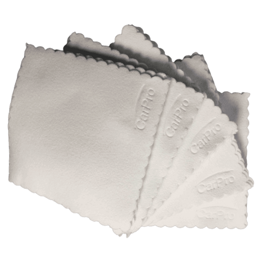 Six white CarPro suede microfiber applicator pads with scalloped edges stacked in a fan shape