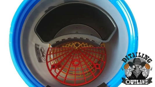 Top view of a blue automotive detailing bucket with a red grit guard and yellow grid inside, Detailing Outlaws logo visible