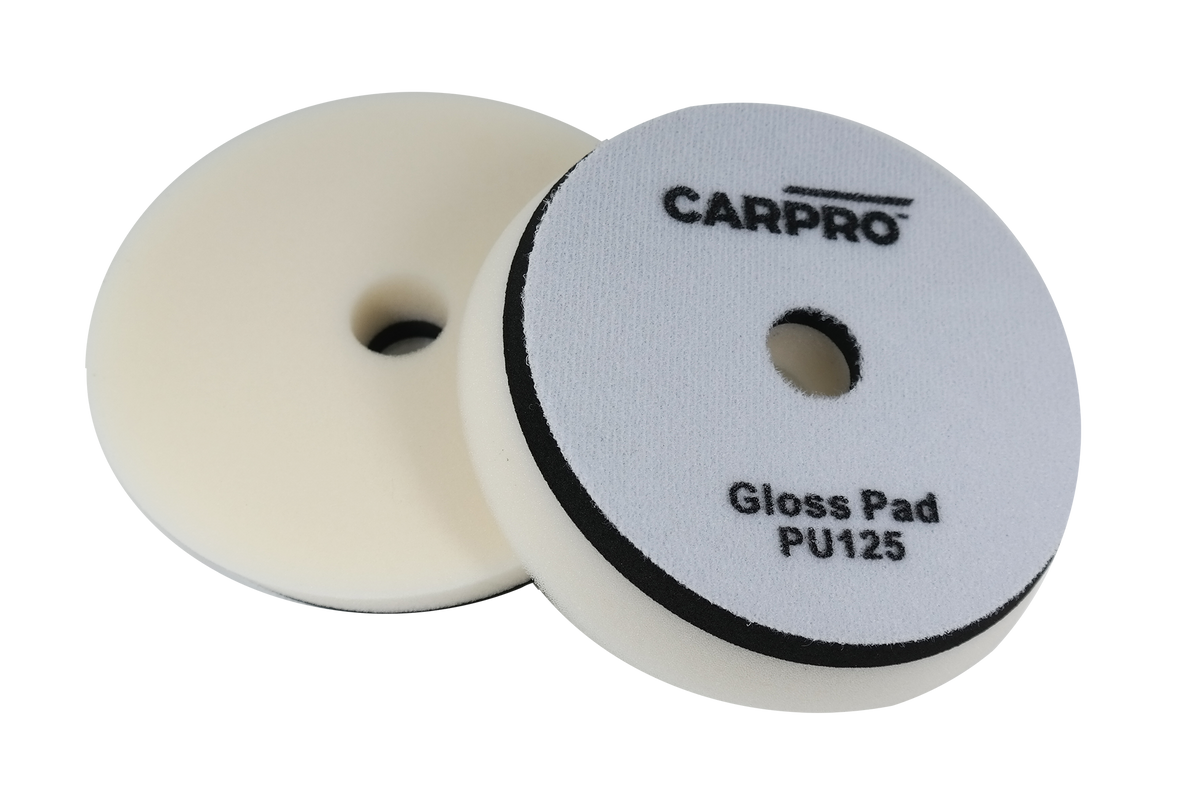 Two CarPro Gloss Pads PU125 foam polishing pads with central holes on a white background