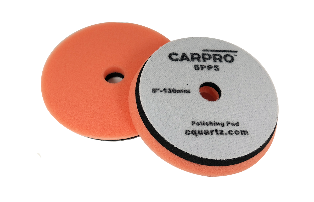 Pair of orange CarPro polishing pads with center holes and gray backing