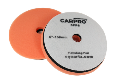 Pair of orange CarPro polishing pads with center holes and gray backing